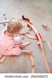 Overhead Shot Of Young Girl At Home Playing With Wooden Train Set Toy