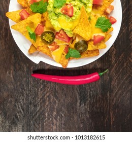 An Overhead Square Photo Of Nachos With Queso, Traditional Mexican Snack, On A Rustic Background With A Place For Text And A Red Hot Chili Pepper