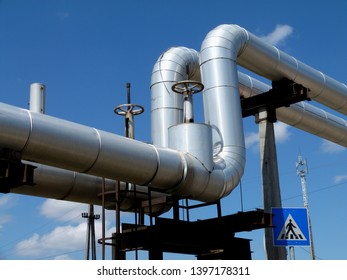 Overhead Steel Pipeline With Aluminum Shroud Covered Gas Or Heating Supply Tubes On Concrete Support. Blue Sky. Natural Gas Supply Shortage And Energy Supply Security Concept. Europe, Russia, Germany.