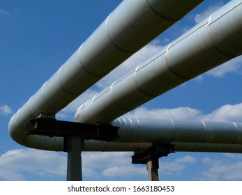 Overhead Steel Pipeline With Aluminum Shroud Covered Gas Or Heating Supply Tubes On Concrete Support. Blue Sky. Natural Gas Supply Shortage And Energy Supply Security Concept. Europe, Russia, Germany.