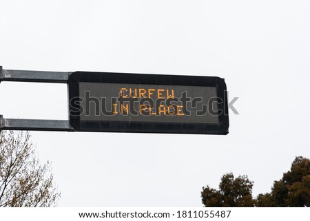 An overhead street sign showing the information about the curfew in place in the city of Melbourne, Australia during the COVID-19 pandemic