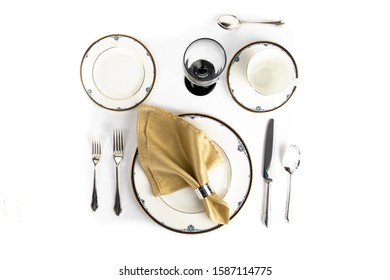 Overhead Top Down View Of A Fine China Place Setting For Dinner With A Gold Napkin Isolated On White