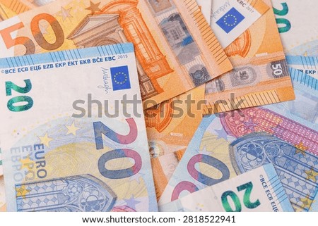 Overhead top down view of twenty and fifty euro banknotes scattered across the table, full frame background pattern representing wealth and finance