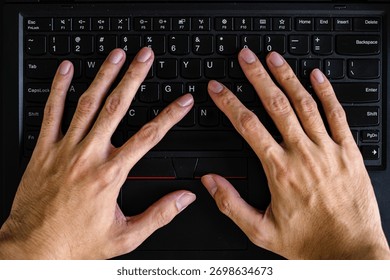 Overhead of two human hands actively typing on a black laptop keyboard, emphasizing the trackpoint, trackpad, and keys for digital work and learning.