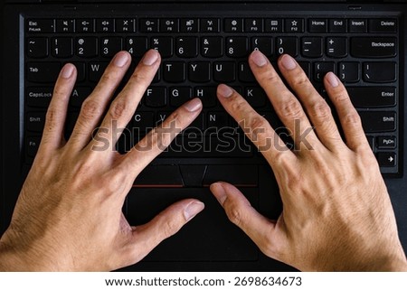 Overhead of two human hands actively typing on a black laptop keyboard, emphasizing the trackpoint, trackpad, and keys for digital work and learning.