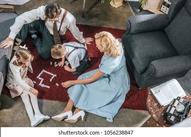 overhead view of 1950s family with two kids playing dominoes together at home