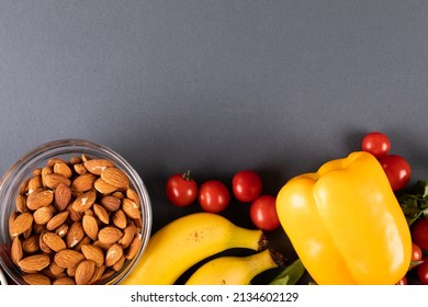 Overhead view of almonds in bowl with banana, cherry tomatoes and yellow bell pepper on table. unaltered, copy space, healthy food, vegetable, raw food and organic concept. - Powered by Shutterstock