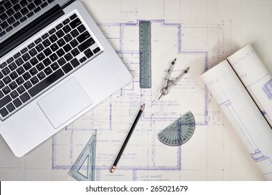 Overhead View Of Architect's Desk With Blueprints And Computer