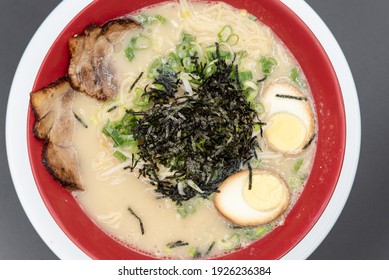 Overhead View Of Arge Bowl Of Spicy Tonkotsu Ramen Served With A Pile Of Seaweed On Top With Braised Pork And Hard Boiled Egg Halves.