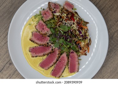 Overhead View Of Artistic Presentation Of Seared Ahi Tuna Slices Arranged In Circular Garnished Plate Of Food.