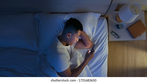 Overhead View Of Asian Man Use Smartphone On Bed At Night