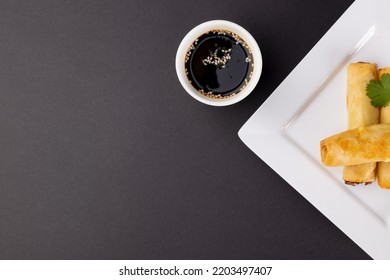 Overhead View Of Asian Spring Rolls On White Plate And Soy Sauce With Copy Space On Grey Background. Asian Tasty Home Cooked Food And Healthy Eating.