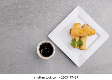 Overhead View Of Asian Spring Rolls On White Plate And Soy Sauce On Grey Background. Asian Tasty Home Cooked Food And Healthy Eating.