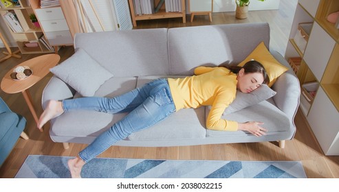 Overhead View of asian woman lying buried her face in couch feels tired in living room at home - Powered by Shutterstock