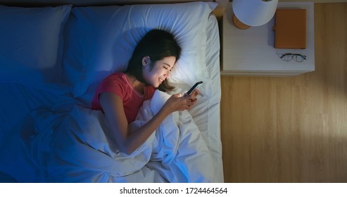 Overhead View of asian woman use smartphone on bed at night - Powered by Shutterstock