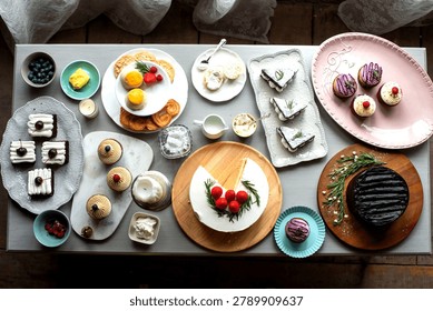 Overhead view of assorted elegant desserts and pastries arranged on serving platters and plates for a stylish dessert buffet.