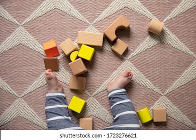Overhead View Of A Baby Playing With Wooden Building Blocks