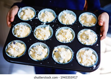 Overhead View Of A Baking Tray With Freshly Prepared Plain Blueberry Muffins Holding By A Child