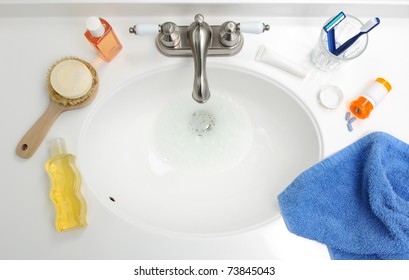 Overhead View Of A Bathroom Sink With Soap, Liquid Gels, Toothbrush, Razor, Medicine, Pills, Towel, And Toothpaste. Horizontal Format.