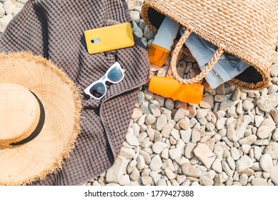 Overhead View Of Beach Stuff Blanket With Sun Protection Cream Straw Hat With Bag