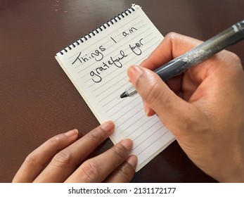 An Overhead View Of A Black Person Holding A Pen And Writing A Gratitude List On A Notepad