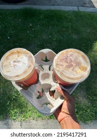 An Overhead View Of A Black Person Holding A Take Away Drink Tray With Two Iced Tea Lattes