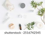 Overhead view of blank cosmetic bottles, brown glass cosmetic dropper bottle for face serum or oil, pistachio branches, linen bag on a white background. Face care routine.