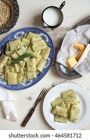 Overhead View Of A Blue China Platter Filled With Pesto Rigatoni. Shown With Small White Serving Plate, Antique Fork, Cheese, Creamer And Silver Bowl Containing Pine Nuts. 