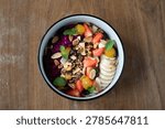 Overhead view of a bowl filled with fruit salad and granola