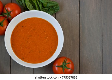 Overhead View Of A Bowl Of Hearty And Delicious Homemade Tomato Soup With Tomatoes And Basil.