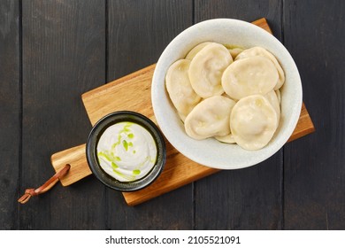 Overhead View Of A Bowl Of Pelmeni With Curd With Sour Cream On A Wooden Serving Board