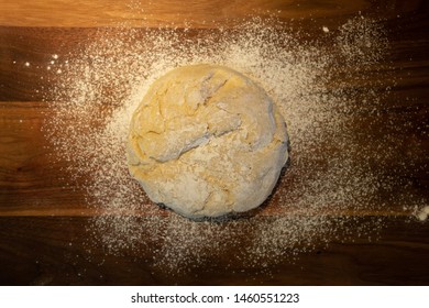 Overhead View Of Bread Dough Ball On A Wooden Cutting Board With Flour.