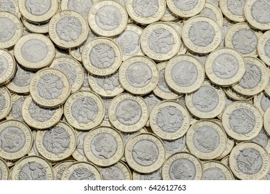 Overhead view of British pound coins. Many in an untidy pile. New UK bimetallic currency introduced in March 2017 viewed from above.