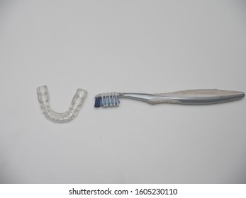 An Overhead View Of A Bruxism Guard And A Toothbrush Isolated Against A Plain White Background