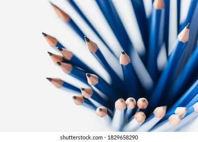 Overhead view of bunch of sharpened blue pencils on white paper.
