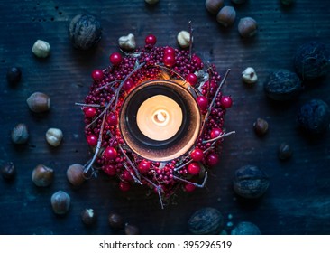 Overhead view of burning candle surrounded by berry wreath and nuts - Powered by Shutterstock