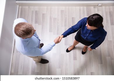 An Overhead View Of Business Partners Standing Over Hardwood Floor Shaking Hands