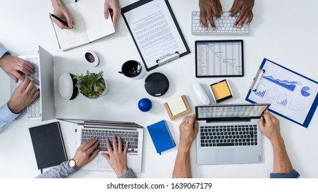 Overhead View Of Businesspeople's Hands On Desk With Laptops And Digital Tablet In Office - Shutterstock ID 1639067179