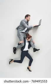 Overhead View Of Businesswoman Carrying Businessman That Working On Laptop Isolated On Grey