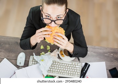 Overhead View Of Businesswoman eating At Computer In Office at work place. The modern pace of life there is no time for healthy eating