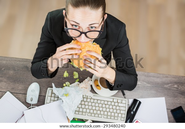Overhead View Of Businesswoman eating At Computer\
In Office at work place. The modern pace of life there is no time\
for healthy eating