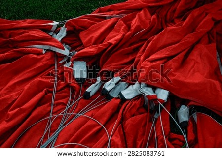 Overhead view of cables and attachments on the fabric of a red hot air balloon.