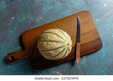 Overhead View Of A Cantaloupe Melon, On A Wooden Cutting Board.