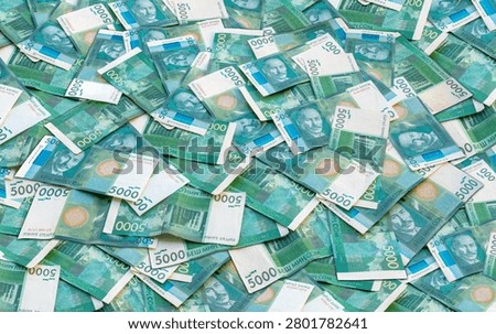 Overhead view captures a dense pile of 5000 Kyrgyzstani som banknotes, primarily green and white with blue accents.