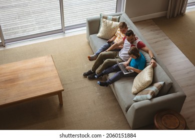 Overhead View Of Caucasian Father And Two Sons Using Laptop And Digital Tablet At Home. Childhood, Technology And Home Concept