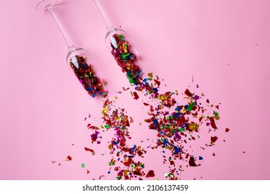 Overhead View Of Champagne Flutes With Scattered Multi Colored Confetti On Pink Background. Celebration, Party And Copy Space.