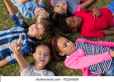 Overhead view of children with arms raised lying on field in yard - Shutterstock ID 702265834