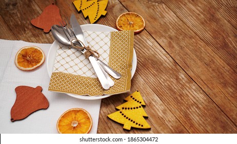 Overhead view of Christmas table setting over wooden table with copy space. White plate with dry oranges and wooden christmas figurines - Powered by Shutterstock