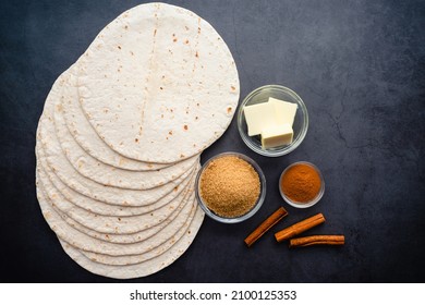 Overhead View Of Cinnamon Sugar Tortilla Chips Ingredients: Flour Tortillas, Butter, Brown Sugar, And Cinnamon On A Dark Background