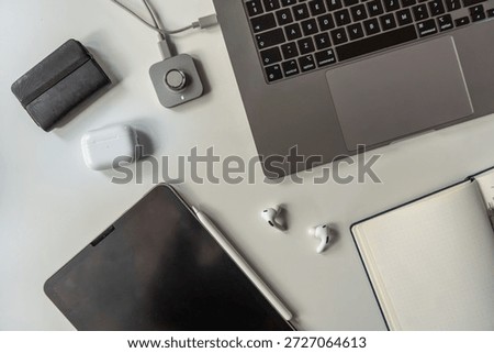 Overhead view of a clean workspace featuring digital devices, wireless accessories, earbuds, and a smart ring charging station. Contemporary productivity and lifestyle setup.